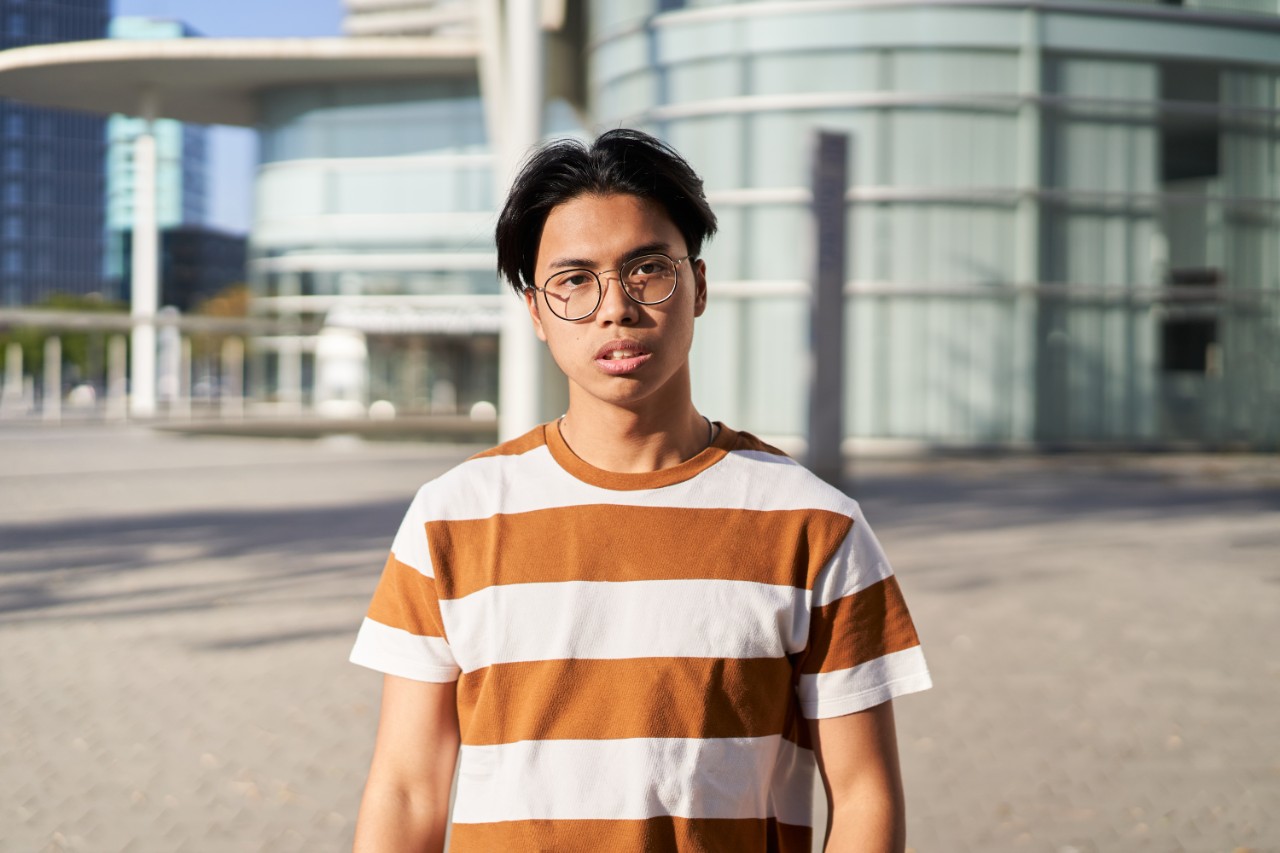 Serious asian Student. Guy looking at the camera outdoors on campus of university. Ethnicity people. High quality photo