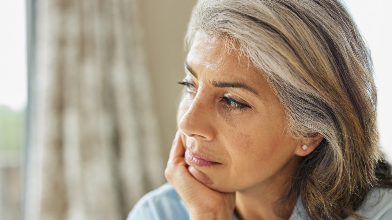 Head And Shoulders Shot Of Thoughtful Mature Woman Looking Out Of Window At Home